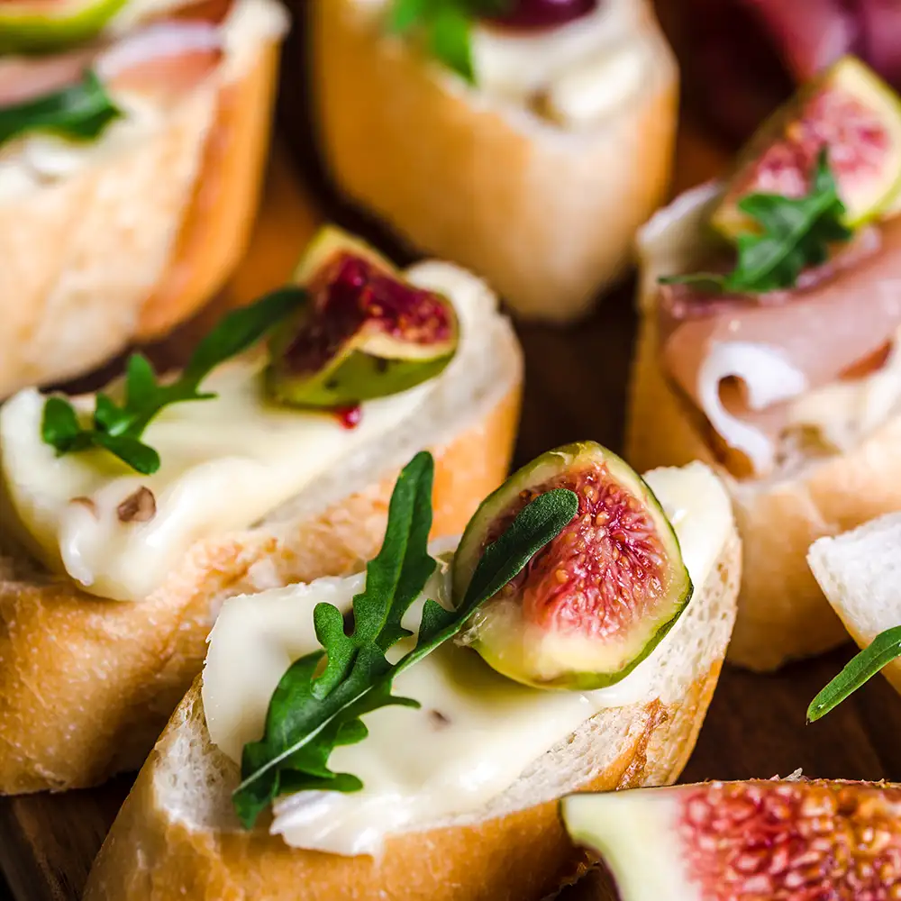 Traditionelle Tapas aus Spanien oder italienische Bruschetta mit Käse, Fleisch und Feigen. Partyessen auf Catering-Platte.